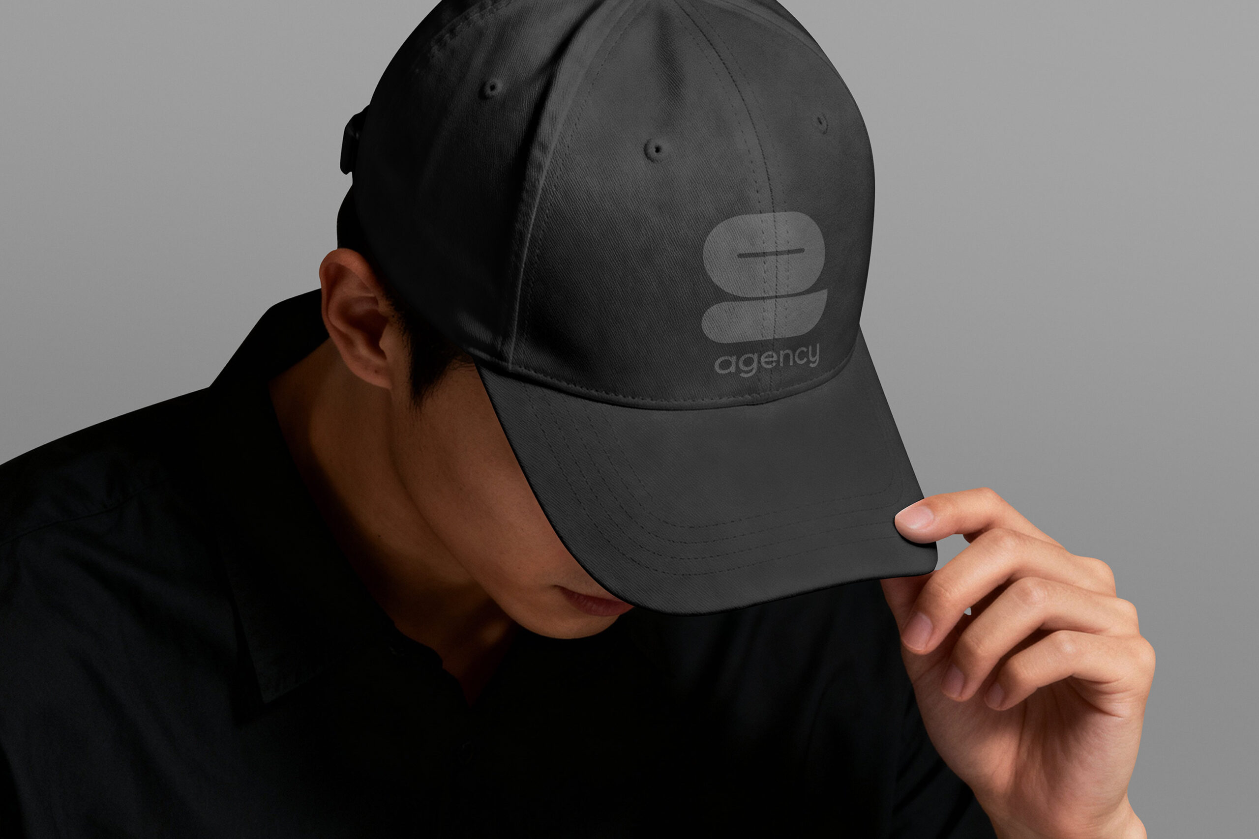 A man in a black hat adorned with the Nine Agency logo, highlighting the brand's identity and fashion appeal.