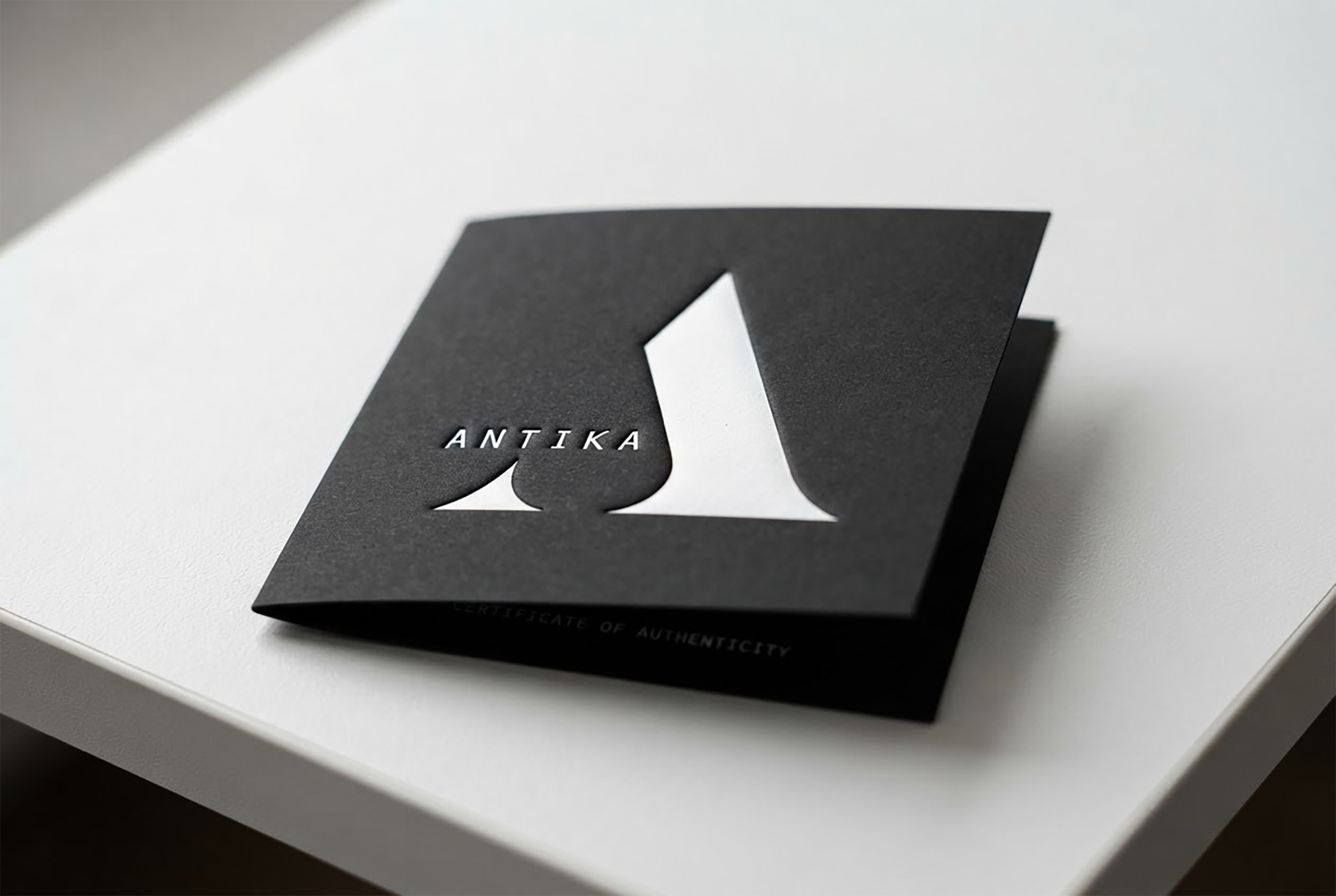 A black 2 fold price card featuring a prominent letter "A" in a modern font, representing the ANTIKA brand.