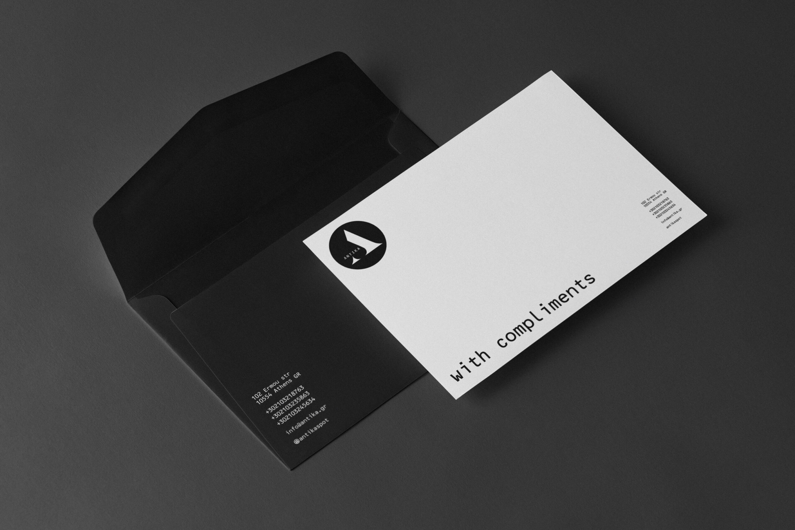 An envelope in black and white displaying the Antika Compliments logo prominently.