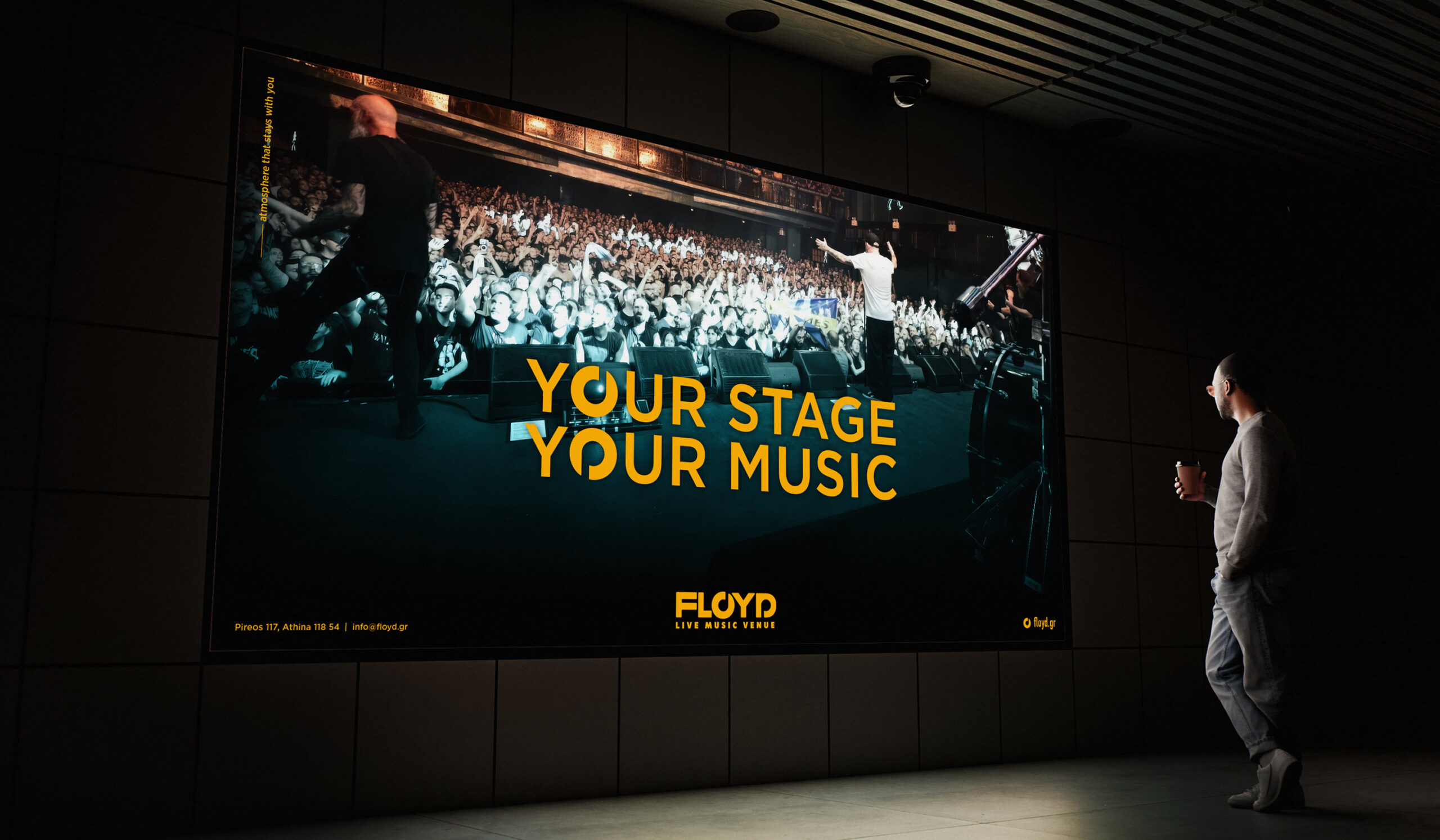 A man poses in front of a vibrant LED screen that reads "Your Stage, Your Music" at Floyd Live Music Venue.