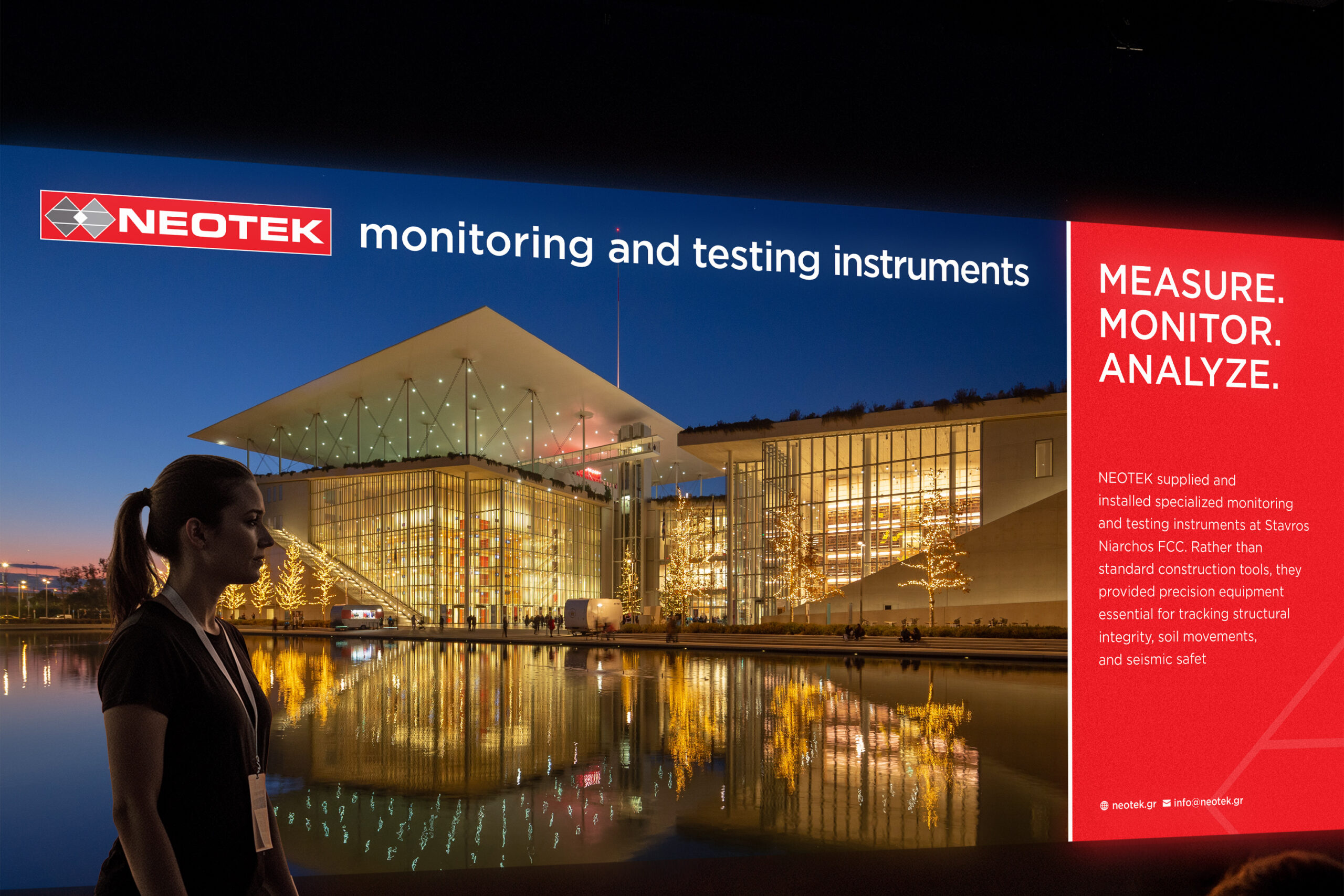 A woman presents in front of a large screen that reads "Monitoring and Testing" during a conference session.