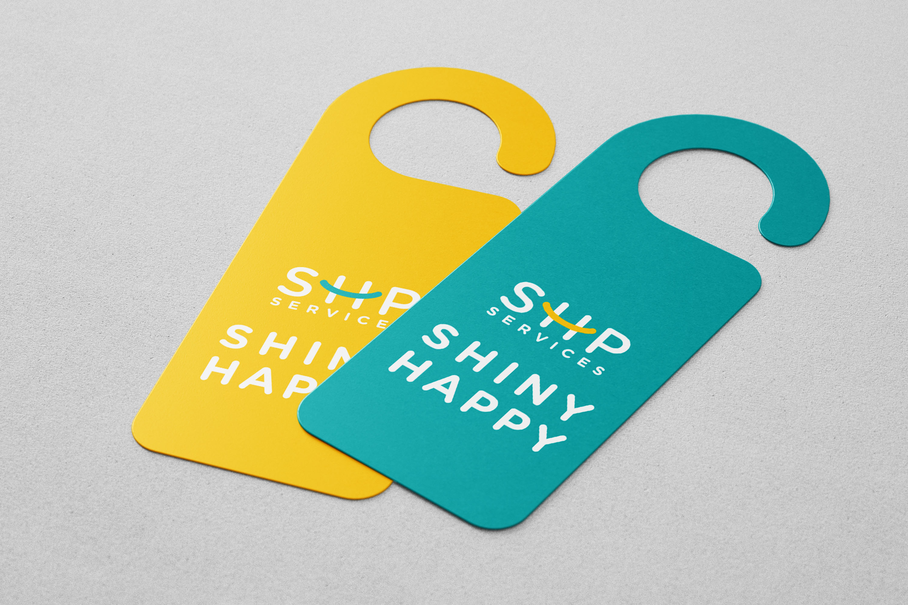 A pair of door hangers featuring the text "Shiny Happy" prominently displayed in vibrant colors.