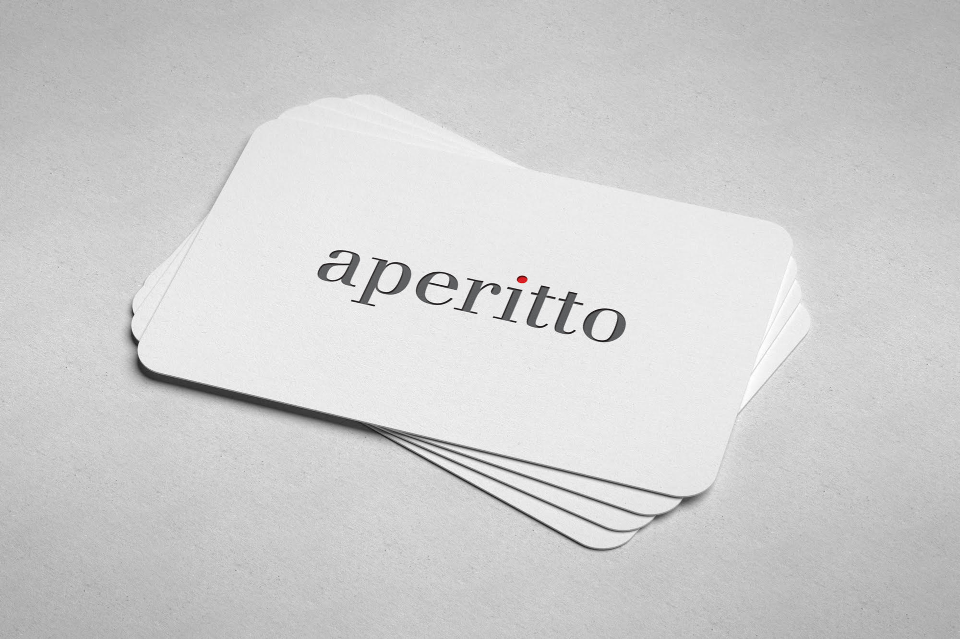 A close-up view of a stack of Aperitto business cards resting on a white background, highlighting the front side.